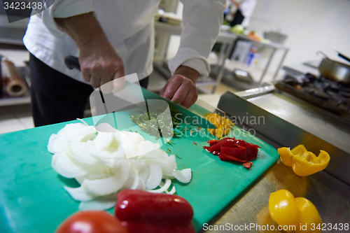 Image of chef in hotel kitchen  slice  vegetables with knife