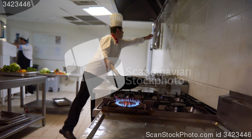 Image of chef in hotel kitchen prepare food with fire