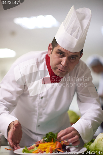 Image of chef in hotel kitchen preparing and decorating food