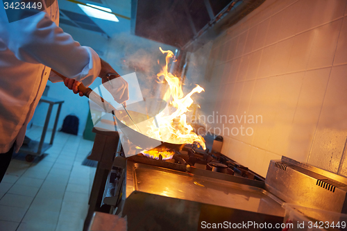 Image of chef in hotel kitchen prepare food with fire