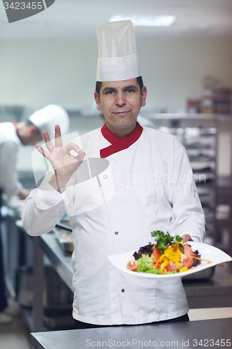 Image of chef in hotel kitchen preparing and decorating food