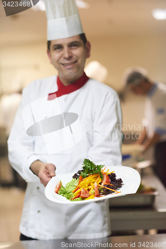 Image of chef in hotel kitchen preparing and decorating food