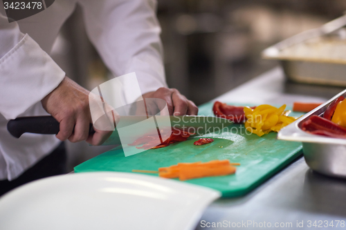 Image of chef in hotel kitchen  slice  vegetables with knife