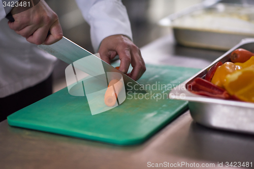 Image of chef in hotel kitchen  slice  vegetables with knife