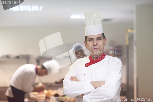 Image of chef in hotel kitchen preparing and decorating food