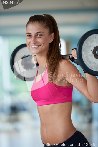Image of young woman in fitness gym lifting  weights