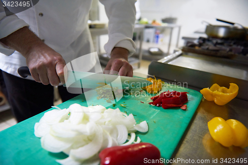 Image of chef in hotel kitchen  slice  vegetables with knife