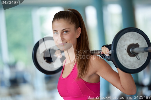 Image of young woman in fitness gym lifting  weights