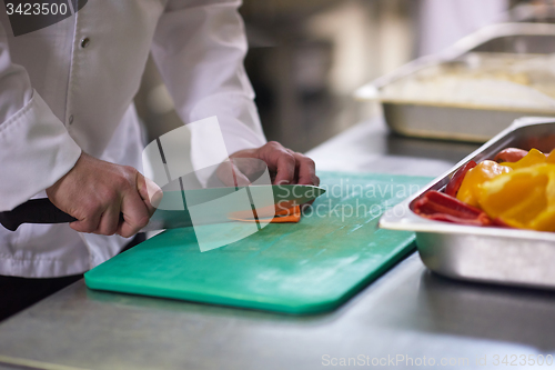 Image of chef in hotel kitchen  slice  vegetables with knife