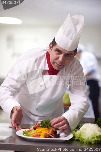 Image of chef in hotel kitchen preparing and decorating food