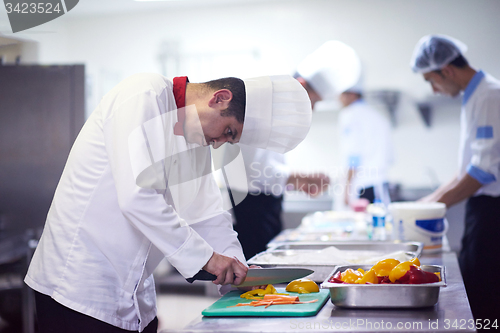 Image of chef in hotel kitchen  slice  vegetables with knife