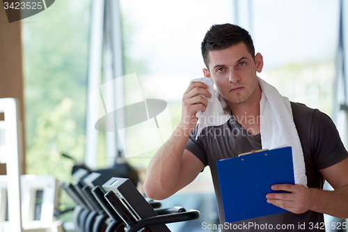 Image of trainer with clipboard standing in a bright gym