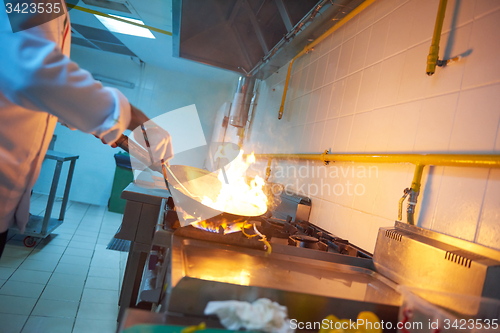 Image of chef in hotel kitchen prepare food with fire