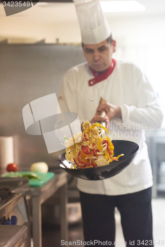 Image of chef in hotel kitchen prepare food with fire