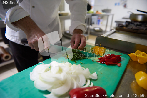 Image of chef in hotel kitchen  slice  vegetables with knife