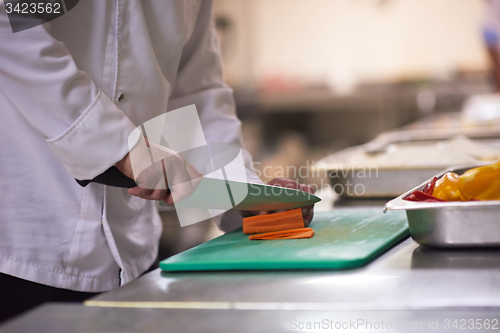 Image of chef in hotel kitchen  slice  vegetables with knife