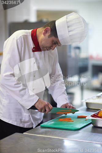 Image of chef in hotel kitchen  slice  vegetables with knife