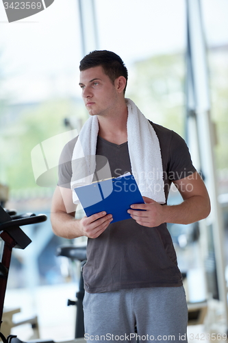 Image of trainer with clipboard standing in a bright gym