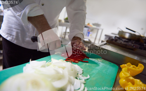 Image of chef in hotel kitchen  slice  vegetables with knife