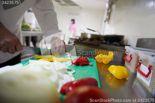 Image of chef in hotel kitchen  slice  vegetables with knife