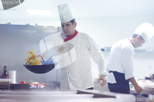 Image of chef in hotel kitchen prepare food with fire