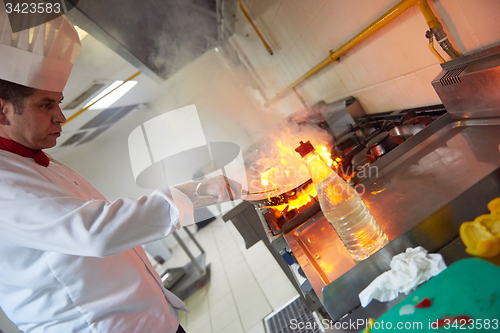 Image of chef in hotel kitchen prepare food with fire