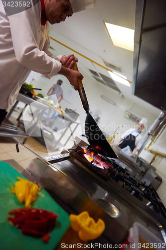 Image of chef in hotel kitchen prepare food with fire