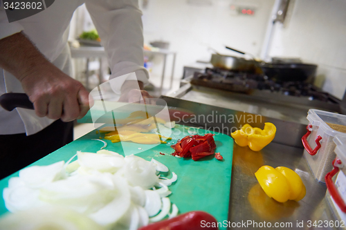 Image of chef in hotel kitchen  slice  vegetables with knife