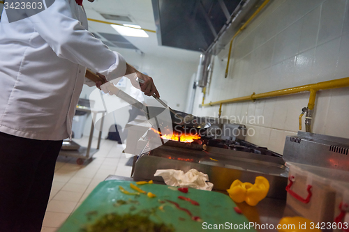 Image of chef in hotel kitchen prepare food with fire