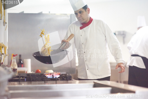 Image of chef in hotel kitchen prepare food with fire