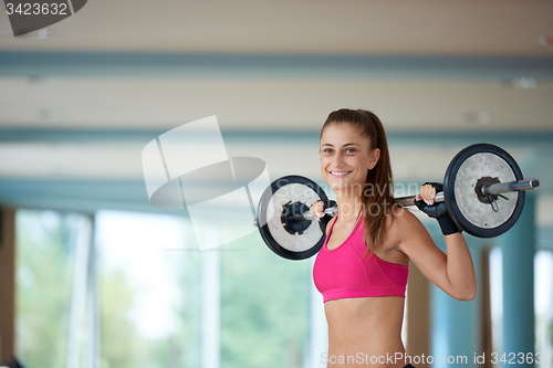 Image of young woman in fitness gym lifting  weights