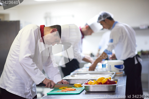 Image of chef in hotel kitchen  slice  vegetables with knife