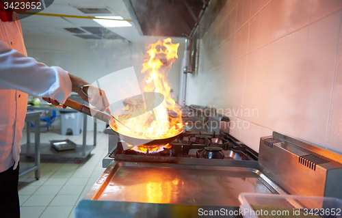 Image of chef in hotel kitchen prepare food with fire