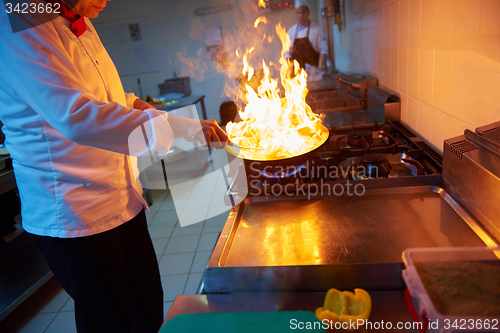 Image of chef in hotel kitchen prepare food with fire