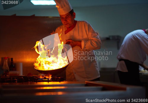 Image of chef in hotel kitchen prepare food with fire