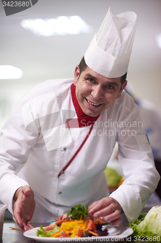 Image of chef in hotel kitchen preparing and decorating food