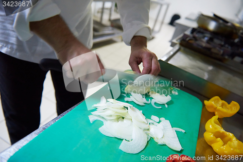 Image of chef in hotel kitchen  slice  vegetables with knife