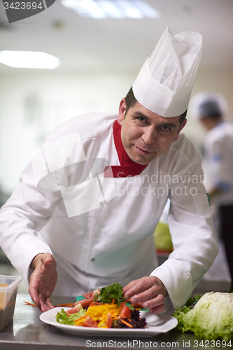 Image of chef in hotel kitchen preparing and decorating food