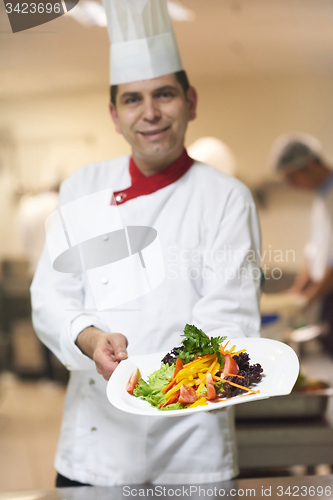 Image of chef in hotel kitchen preparing and decorating food