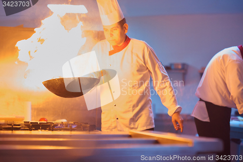 Image of chef in hotel kitchen prepare food with fire