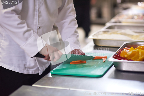 Image of chef in hotel kitchen  slice  vegetables with knife