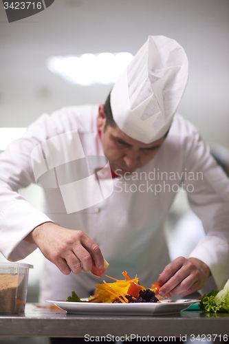 Image of chef in hotel kitchen preparing and decorating food