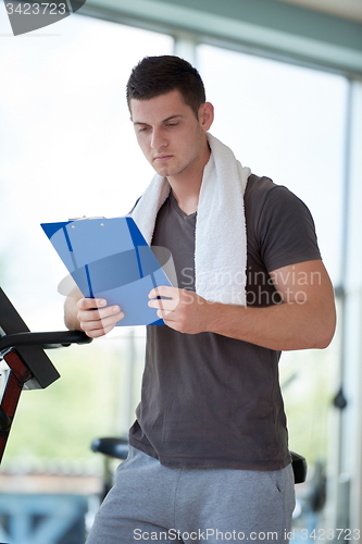 Image of trainer with clipboard standing in a bright gym