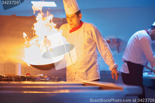 Image of chef in hotel kitchen prepare food with fire