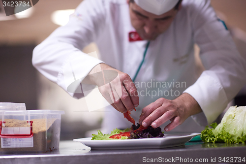 Image of chef in hotel kitchen preparing and decorating food