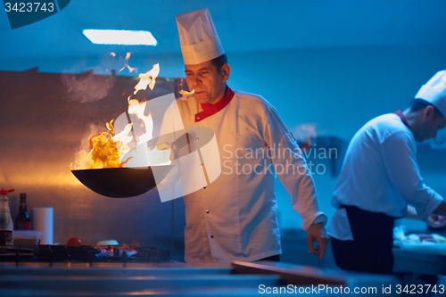 Image of chef in hotel kitchen prepare food with fire