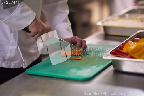 Image of chef in hotel kitchen  slice  vegetables with knife