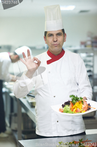 Image of chef in hotel kitchen preparing and decorating food