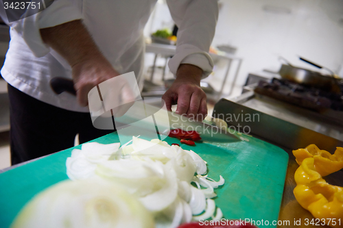 Image of chef in hotel kitchen  slice  vegetables with knife