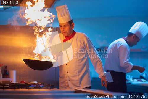 Image of chef in hotel kitchen prepare food with fire